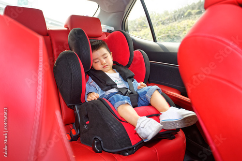 A little boy was sitting in a car safety seat on the bed