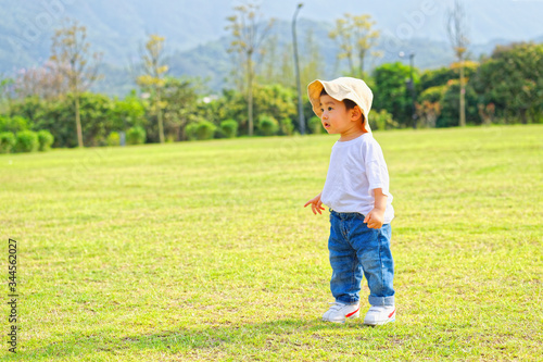 The little boy in a hat in the outdoor lawn 