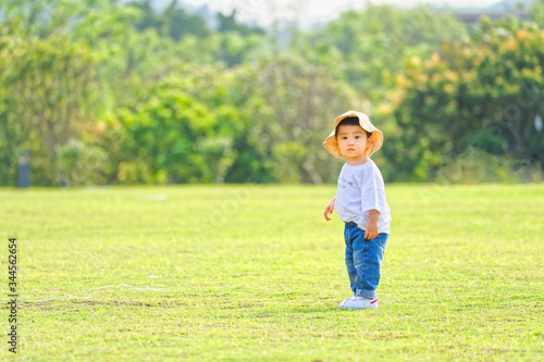 The little boy in a hat in the outdoor lawn 