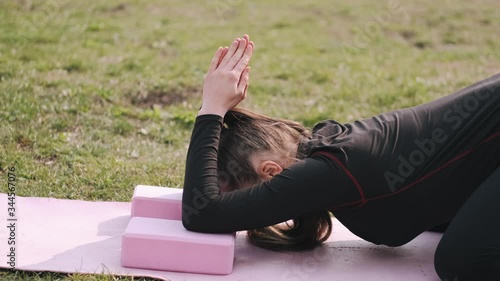 A sporty woman is doing morning exercise.She is stretching on a mat outside.The typical kind of meditation. photo