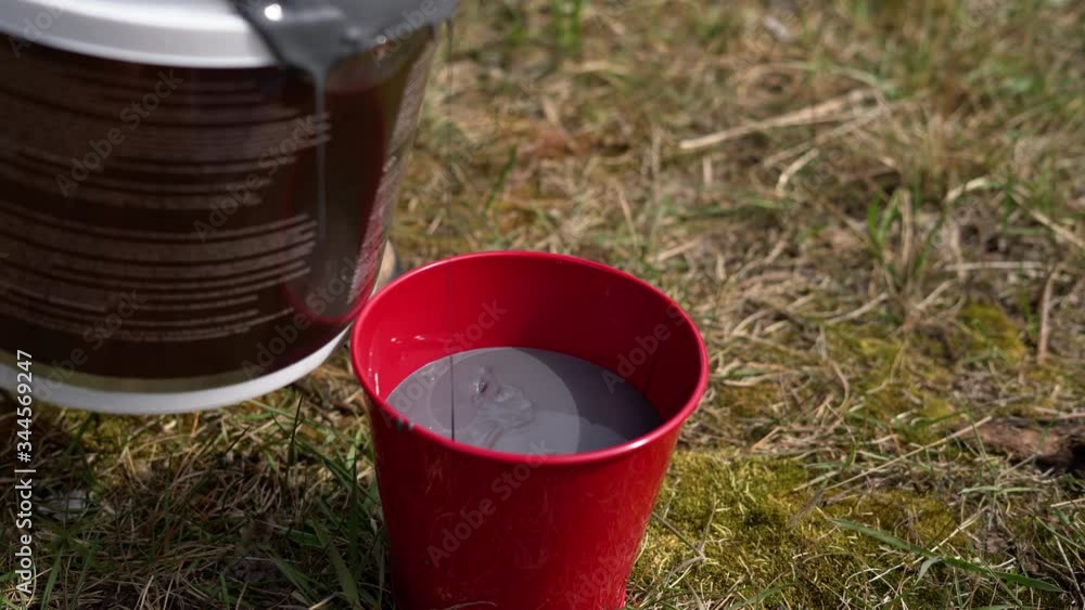 Close up of pouring paint into a bucket outside. Home renovation Close up of pouring paint into a bucket outside. Home renovation