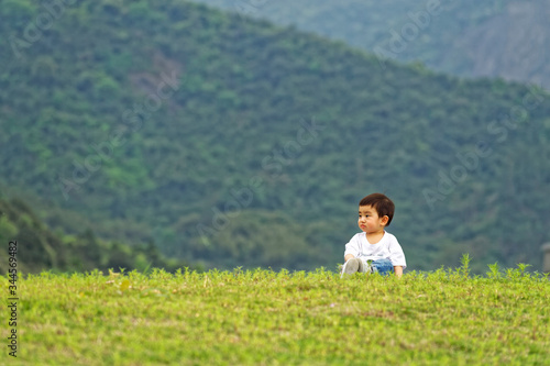 A little boy sitting on the grass