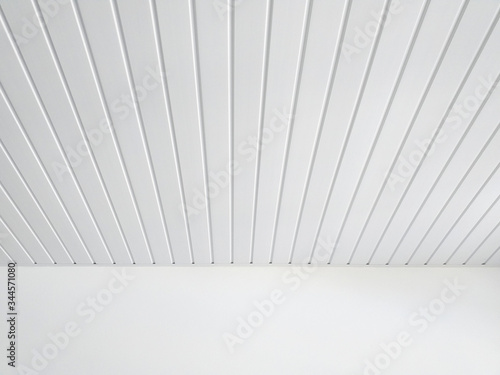 Perspective of white wood sheeting ceiling and smooth white wall in Caribbean construction. White ceiling beams pattern background.