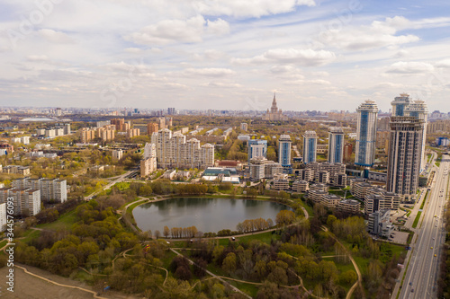 urban neighborhood with a park and a pond in the center removed from a drone