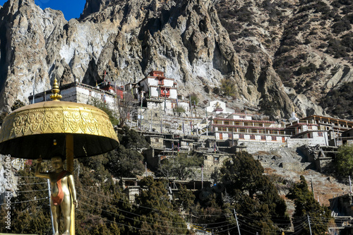 Praken Gompa - an isolated, Buddhist temple hidden from sight in a mountain wall towering above Manang, Nepal. the temple is richly ornated with prayer flags and gold. Spirituality and meditation. photo