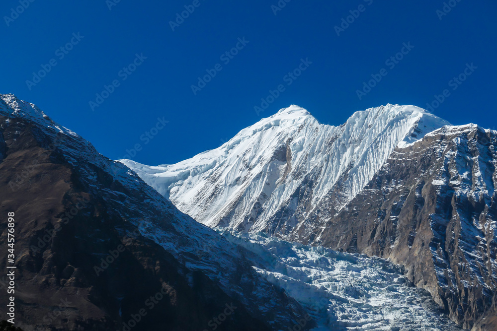 Harsh slopes of Manang Valley, Annapurna Circus Trek, Himalayas, Nepal, with the view on Annapurna Chain and Gangapurna. Dry and desolated landscape.  High mountain peaks, covered with snow.