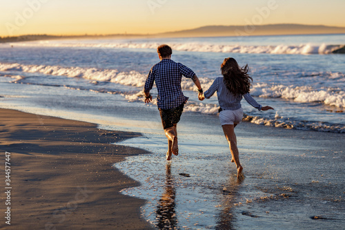 Young couple running on a tropical beach at sunset