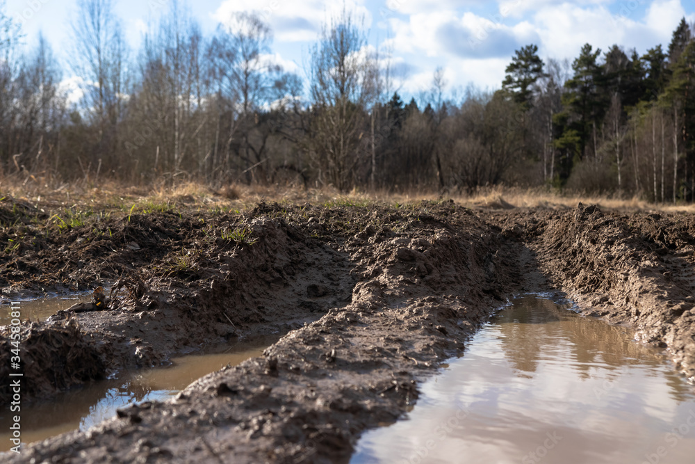 broken dirt road with deep puddles and pits broken dirt road with deep puddles and pits