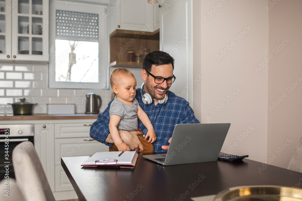 Young father working remotely while babysitting his son. Young father working remotely while babysitting his son.