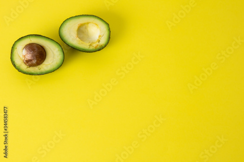 Avocado cut in half on minimalism yellow background