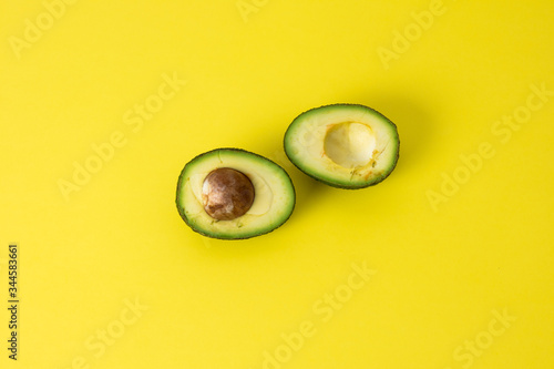 Avocado cut in half on minimalism yellow background