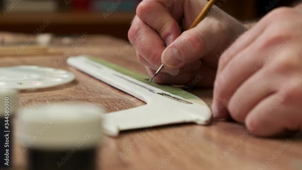 person paints wooden part of passenger jetliner model fuselage with brush at table in classroom close view slow motion person paints wooden part of passenger jetliner model fuselage with brush at table in classroom close view slow motion