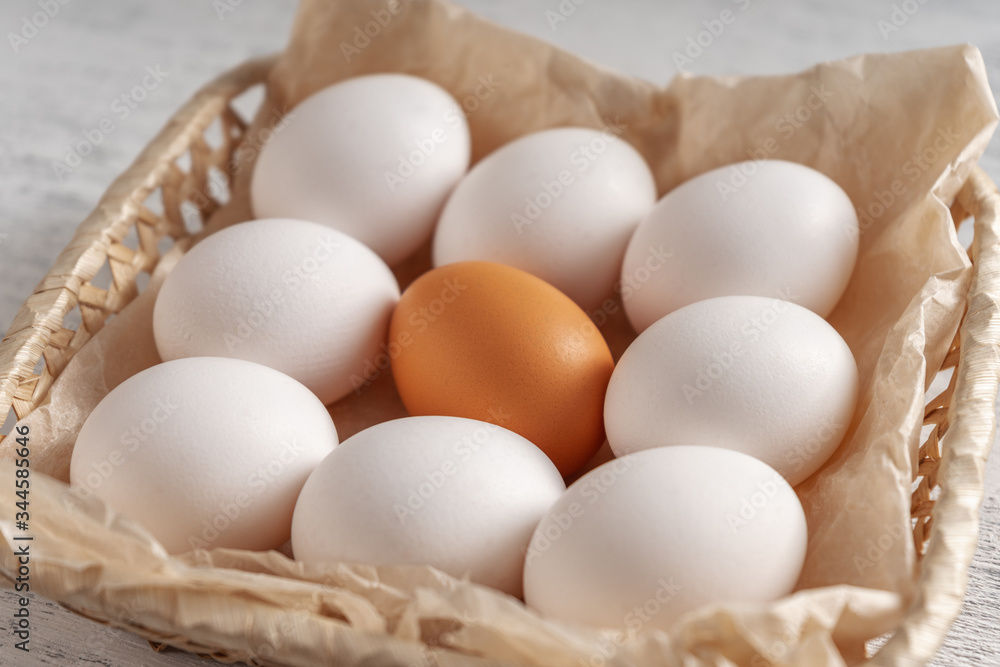 One orange egg among white in one wicker basket. One orange egg among white in one wicker basket.