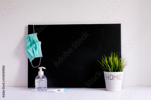 Conceptual of staying clean and safe during virus outbreak. A Hand gel, cirurgical face mask and black chalkboard on a desk. Insert text