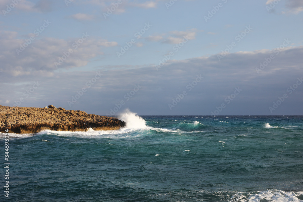 Waves hitting the rocky cliffs in a beach located in Cyprus,This weather might be dangerous for water sports but simultaneously the waves and their splashes are pretty and wild.