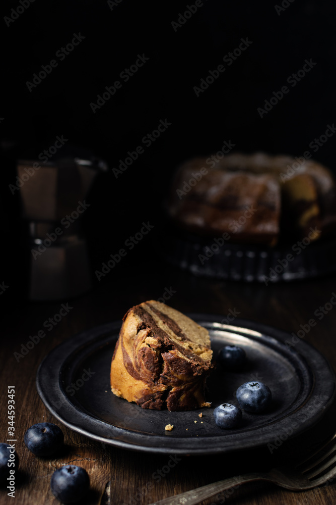 Piece of served chocolate and vanilla marble bundt cake with blueberries and coffee Piece of served chocolate and vanilla marble bundt cake with blueberries and coffee