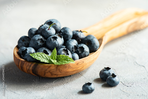 Fresh blueberries in  wooden spoon, macro, concrete background