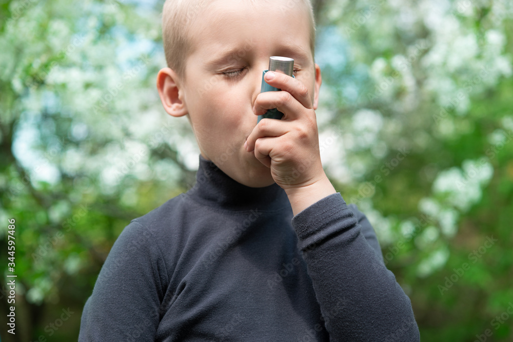 Child uses an asthma attack inhalerin the park Child uses an asthma attack inhalerin the park
