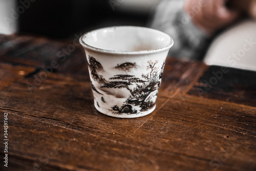 Cup on a wooden table. Ceramic cup for Chinese tea ceremony. A cup for Chinese tea. Hand painted chinese cup
