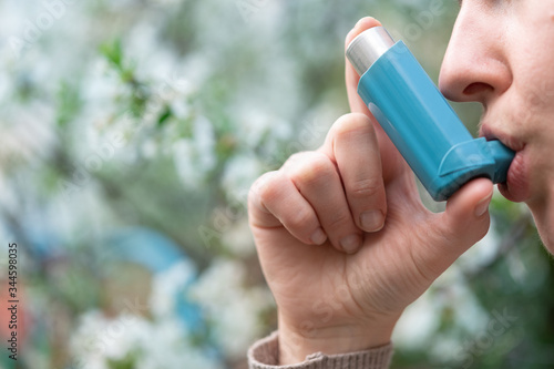 Blond woman with respiratory disease diagnosed with asthma uses an inhaler