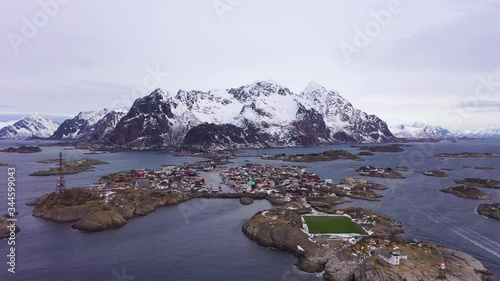 Henningsvaer Fishing Village and Festvagtind Mountain in Winter. Norwegian Sea. Lofoten Islands, Landscape of Norway. Aerial View. Drone Flies Backwards and Upwards photo