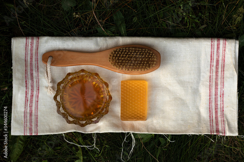 Honey soap lies on a light cotton towel. Nearby lies a body brush and natural honey. Set of accessories for sauna and steam room. The concept of returning to the roots of life and body care