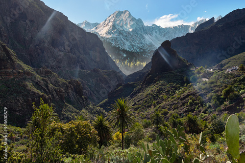 Mountain landscape. A gorge of steep mountains through which a blue sky is visible. The mountains are covered with green vegetation.