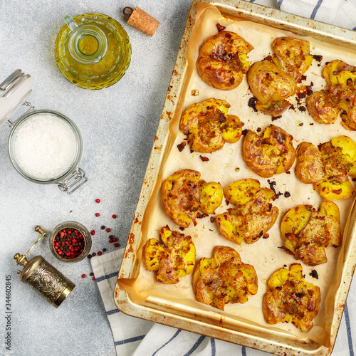 Fotografija Oven baked whole crushed and crusty potato with coarse sea salt, olive oil, garlic, pepper and thyme in metallic tray