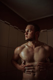 Athletic good looking and attractive man with muscular body standing under running water in shower room