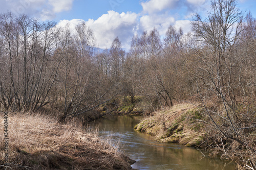 A winding river with steep banks, dry grass and trees