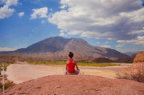 Woman meditating at Quebrada de las Conchas, Cafayate, Salta. Argentina. Desert landscape with mountains, arid climate.