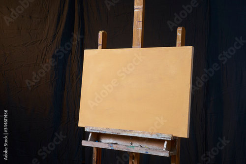 traditional oil Primed Linen stretched canvas panel painting support. Fresh GESSO priming. On an easel . Dark background isolated cool artist studio mockup