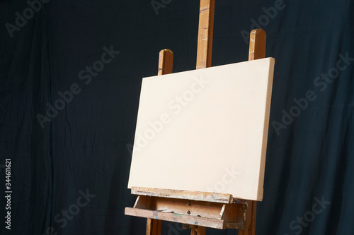 traditional oil Primed Linen stretched canvas panel painting support. Fresh GESSO priming. On an easel . Dark background isolated cool artist studio mockup