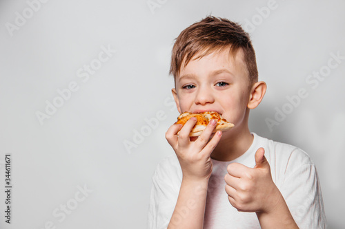 The guy with great pleasure eats a piece of pizza and shows like on a white background