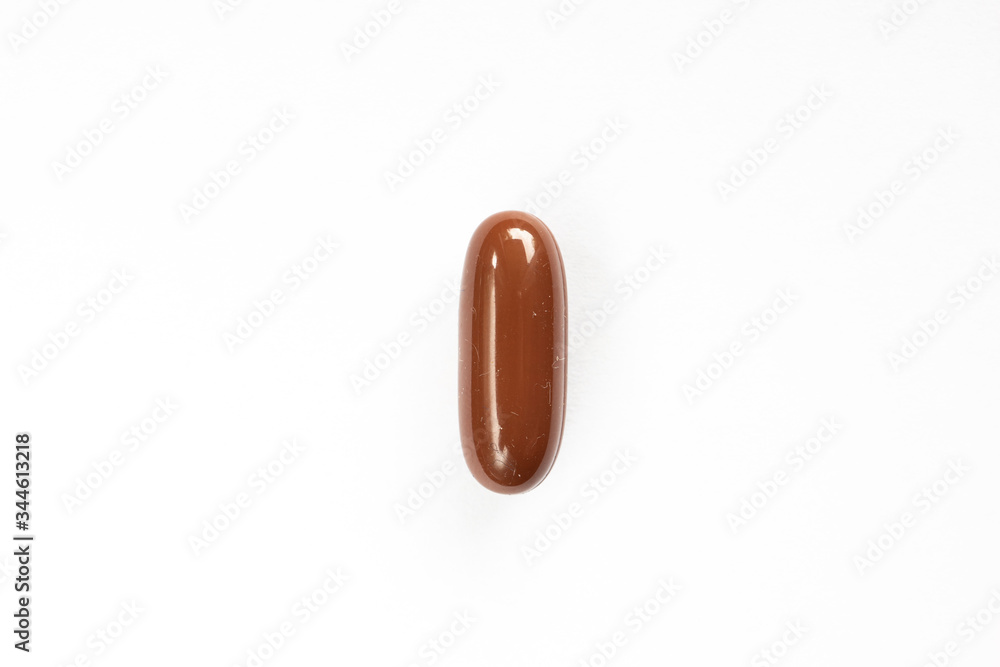 Brown colored medicine soft pill capsule macro close up shot isolated on white surface