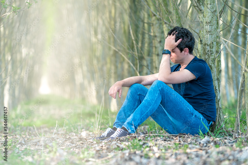 Unhappy man in the forest suffers from depression and frustration of life. copy space Unhappy man in the forest suffers from depression and frustration of life. copy space