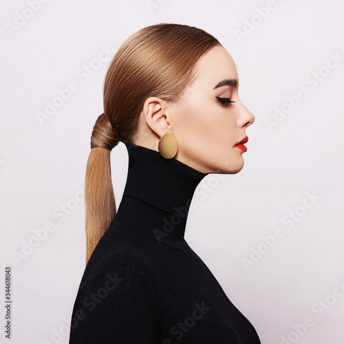 Art portrait of a beautiful, elegant woman in a black turtleneck and gold jewelry