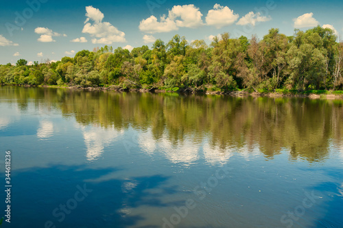 .Summer landscape with the river under the blue sky with white clouds