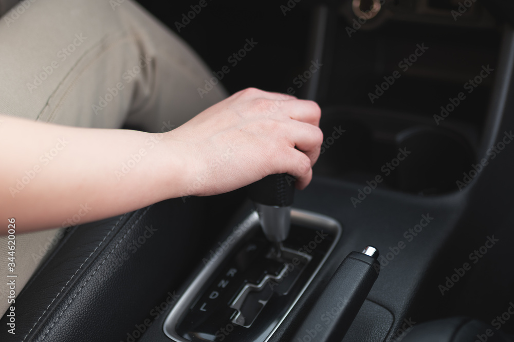 Woman hand on a gearshift knob of her car top view.