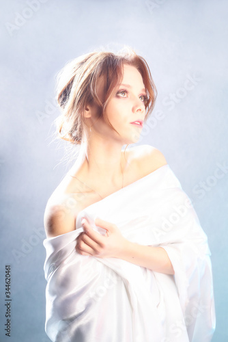 Beautiful girl in a light cloth on a light background. Studio portrait of a gentle
