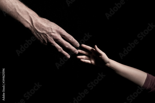 Hands reaching out to each other on dark black background