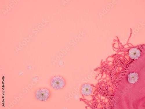 Women's pink scarf and pink flowers on a pink background.