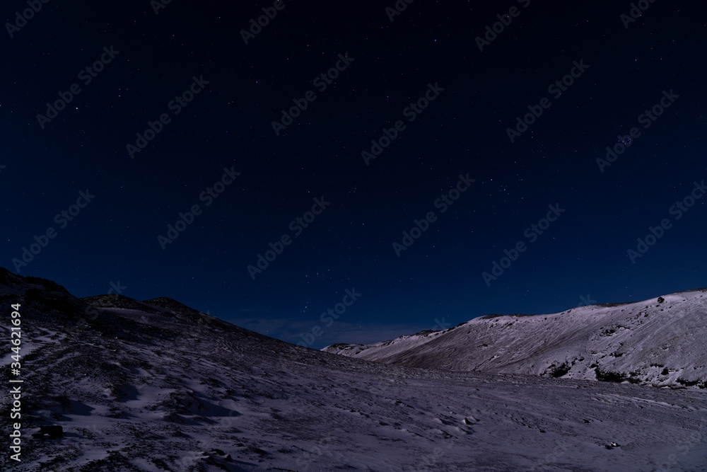 A starry dark blue sky in Iceland over the snow covered rocky landscape. A starry dark blue sky in Iceland over the snow covered rocky landscape.