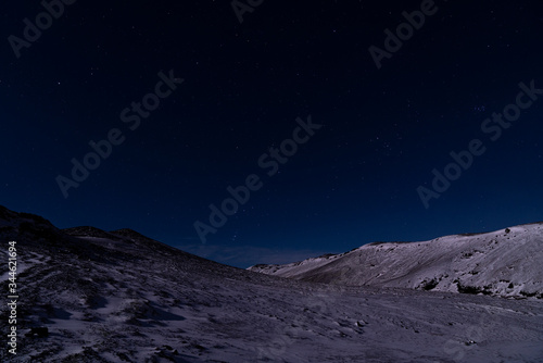 A starry dark blue sky in Iceland over the snow covered rocky landscape.