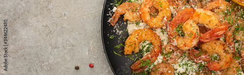 top view of fried shrimps in sauce with dill and lemon in frying pan on grey concrete background, panoramic crop
