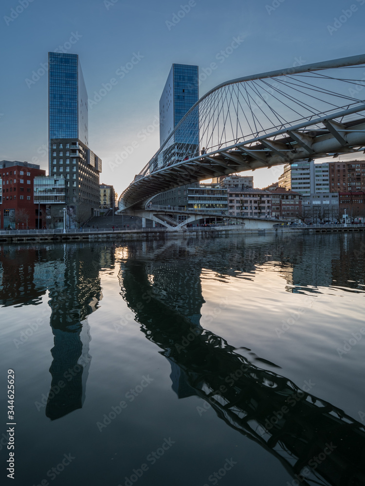 twin skyscrapers with white bridge spanning a river