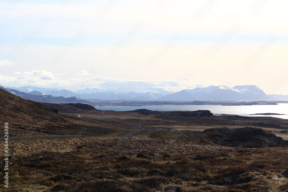 The shoreline of the ocean and beautiful snow-capped mountains on the horizon. The Landscape Of Iceland