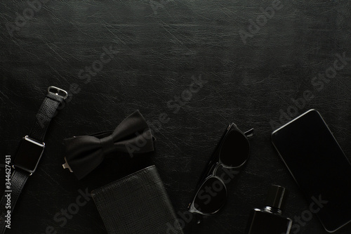 Obraz na płótnie Black monochromatic composition on black background. Mens accessories. Copy space. Watch, phone, sunglasses, purse, perfume, male butterfly. Minimalist black, black friday. Top view. w salonie