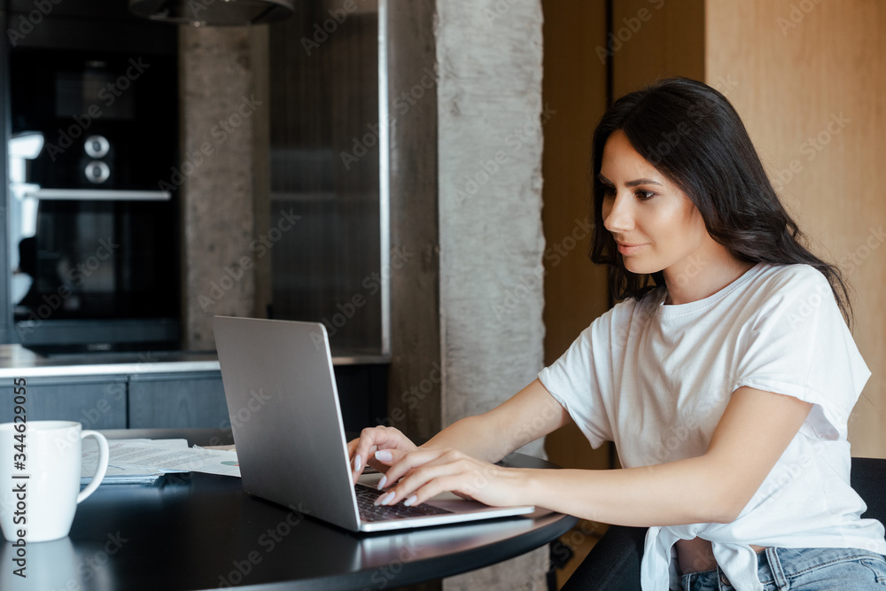 beautiful woman working on laptop with business documents on kitchen on self isolation beautiful woman working on laptop with business documents on kitchen on self isolation