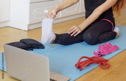 a girl gymnast trains at home via video connection on a laptop, remote sports